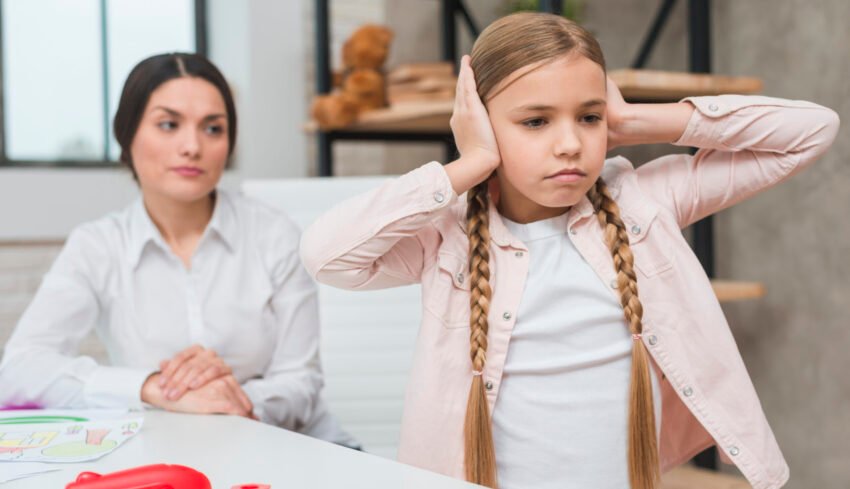 close-up-female-psychologist-looking-annoyed-girl-covering-her-ears-with-two-hands